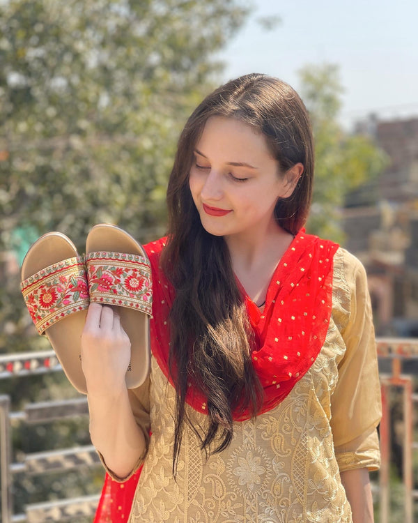 Girl holding Hand embroidered designer Gul sliders wearing ethnic indian outfit